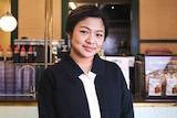A woman standing in front of cashier area and smiling to camera