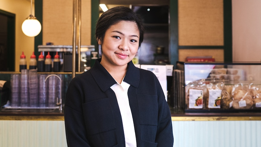 A woman standing in front of cashier area and smiling to camera