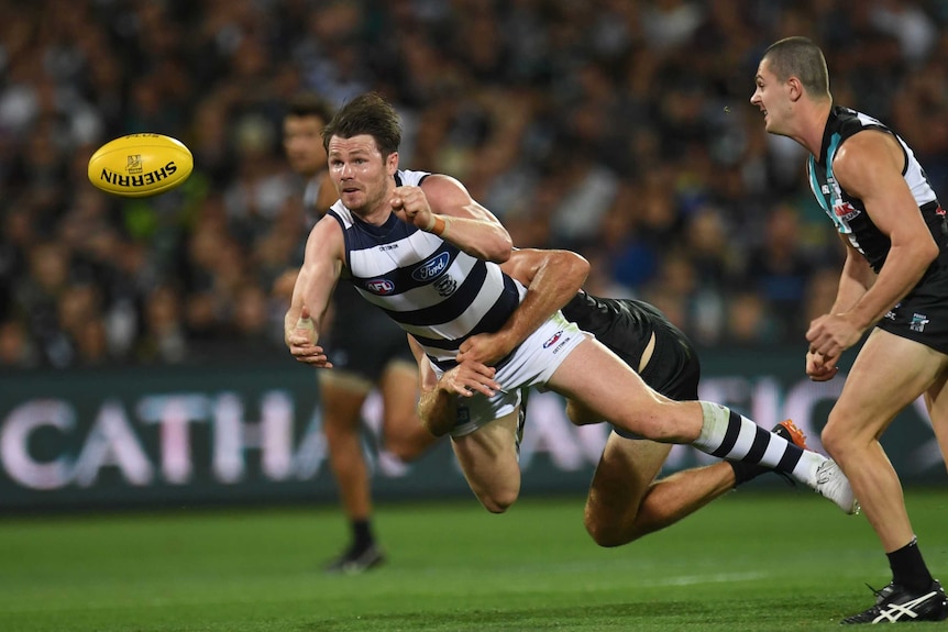 Patrick Dangerfield gets air as he handballs while being tackled