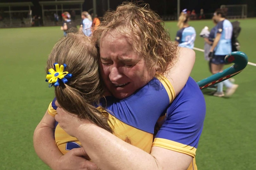 Roxy Tickle being embraced by another player after a women's hockey match