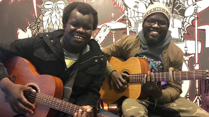 Clement Wetnhiak and Angelo Duot both hold acoustic guitars