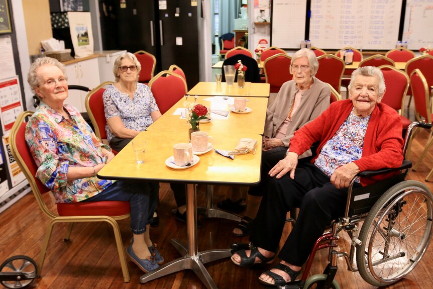 A group of four elderly women sitting around a table in a bistro