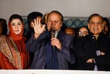Nawaz Sharif speaks with a microphone flanked by his daughter and a former prime minister.