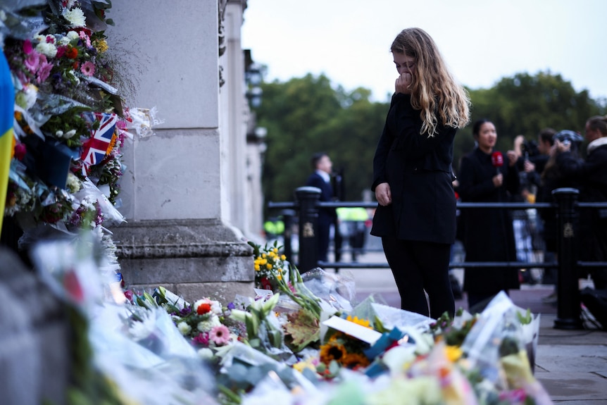 A person reacts near floral tributes placed at Buckingham Palace.