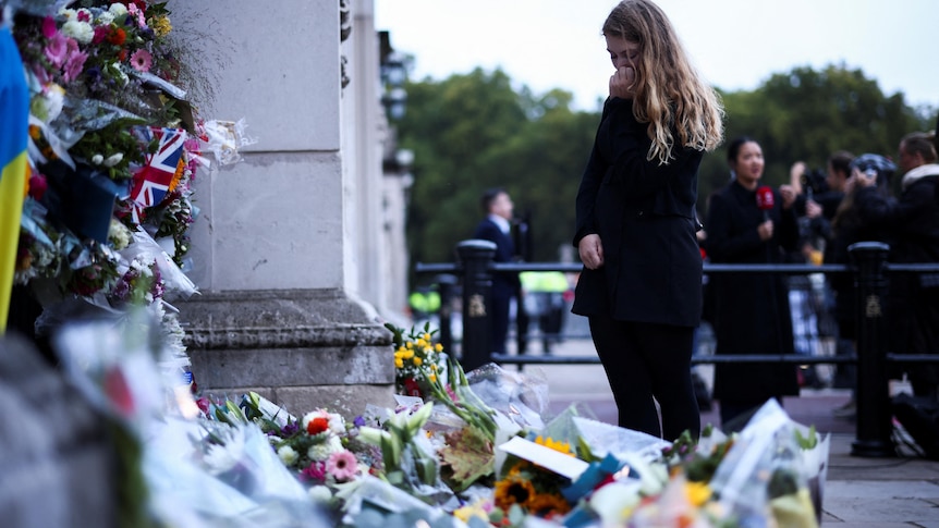 A person reacts near floral tributes placed at Buckingham Palace.