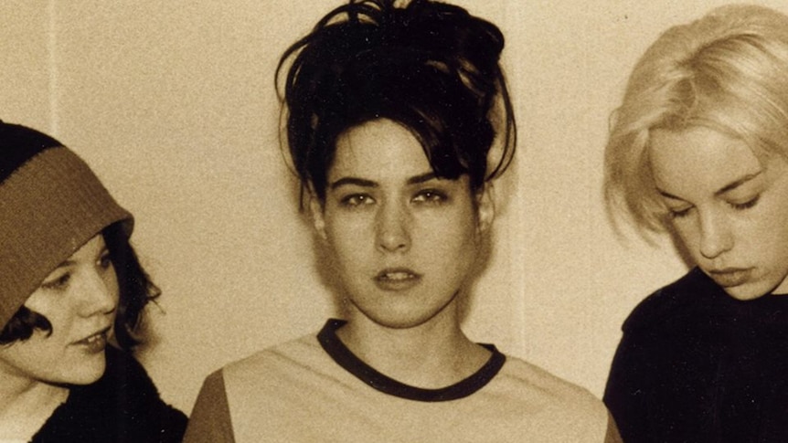 Sepia photo of three members of Bikini Kill from the shoulders up