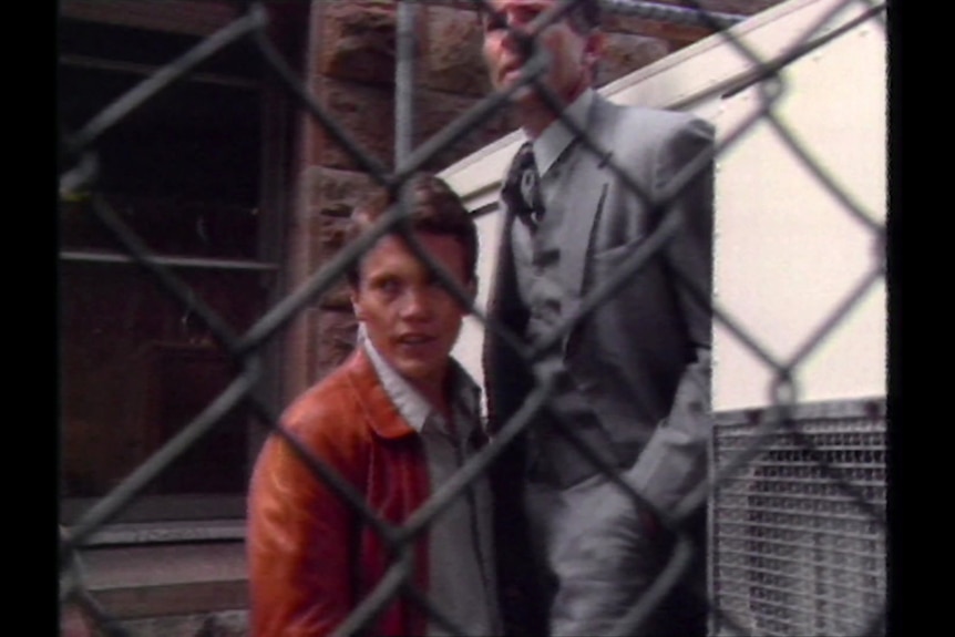 Two men pictured through wire mesh