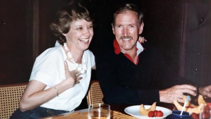 An old photograph showing a middle-aged couple laughing at dinner.