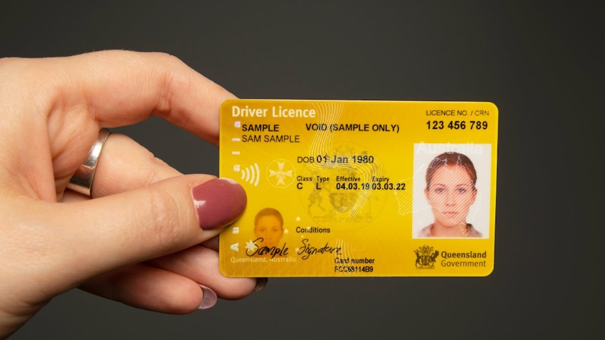 A hand holds up a driver's licence.