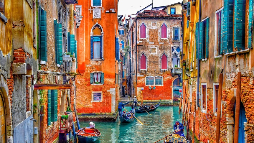 A canal is Venice surrounded by bright pastel homes.