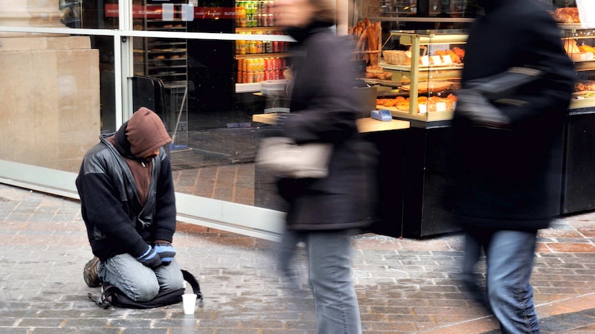 People walk past a homeless man.