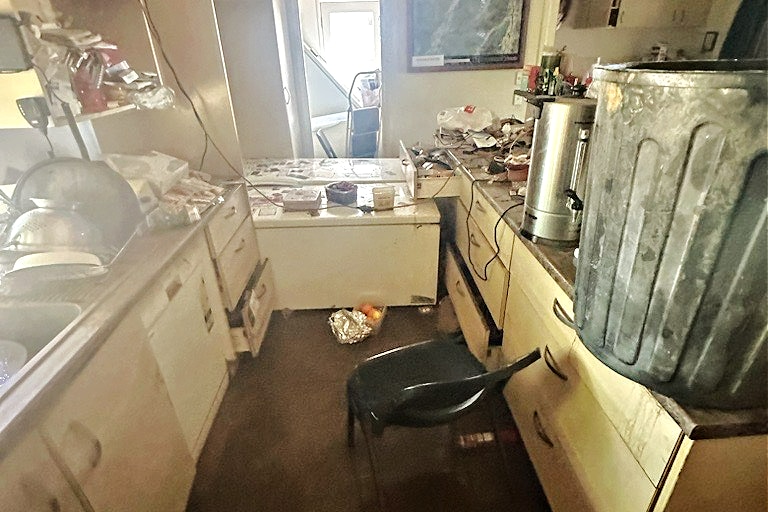 A kitchen in a flooded-damaged house with many items raised onto the bench.