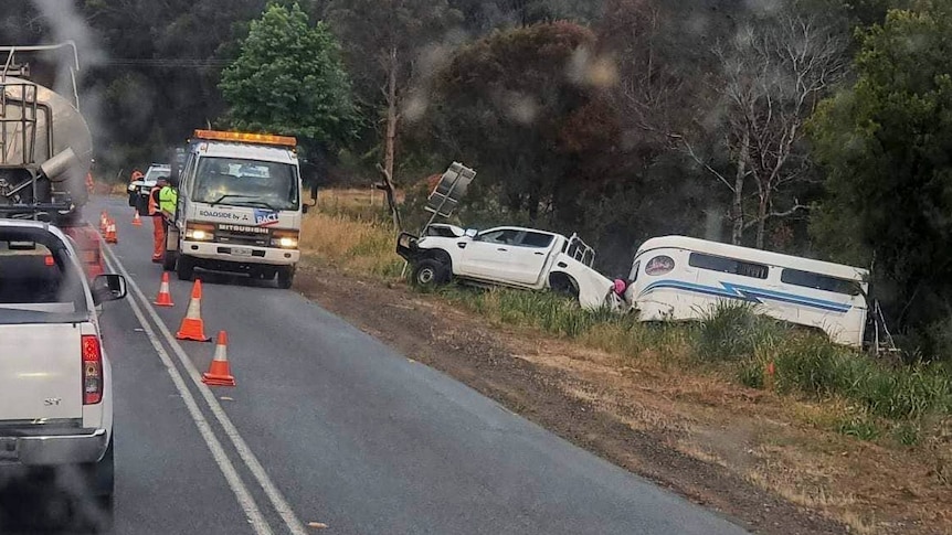 A 4WD towing a horse float leans on the side of an embankment with a tow truck nearby.