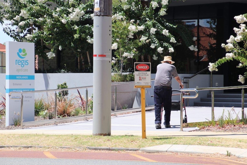 Elderly man with walker approaches the Regis aged care facility in Nedlands.
