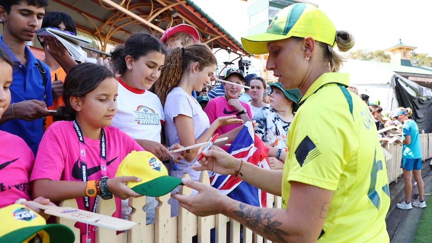 Australia cricketer Ash Gardner signs autographs for young girls in the crowd after a T20 against Pakistan.