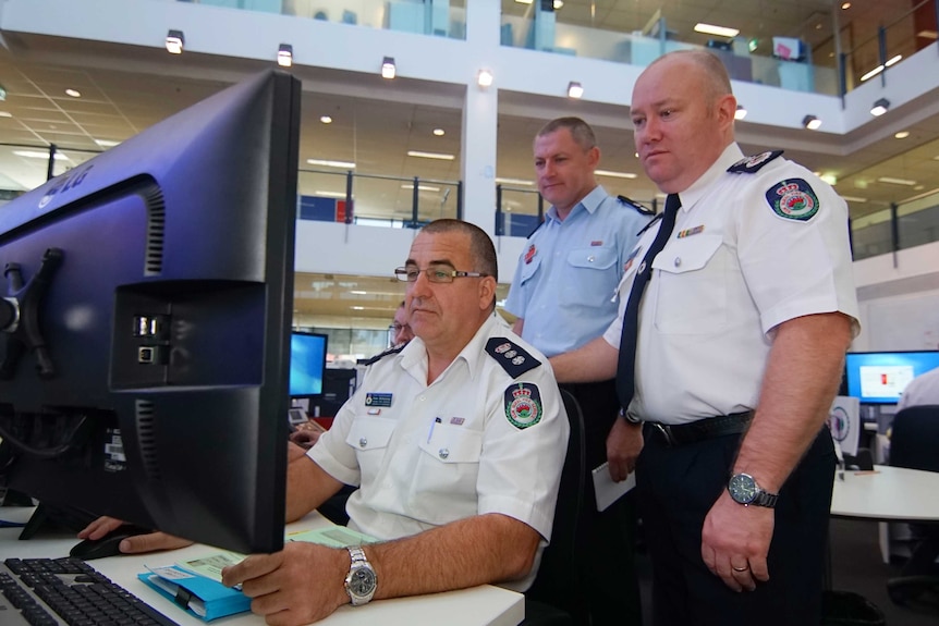 Three men look at a computer screen