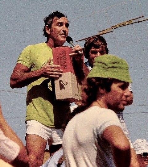 Ted Egan está allí, sosteniendo una caja de cerveza y un micrófono.