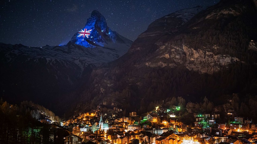 an australian flag image is projected on to the matterhorn mountain at night with houses illuminated below