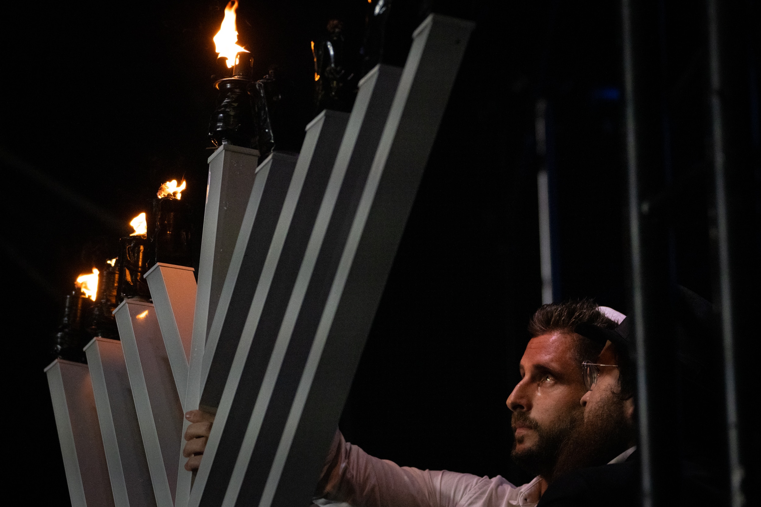 Um homem acendendo uma grande vela de menorá no palco.