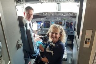A male pilot, a woman and a dog in a plane cockpit
