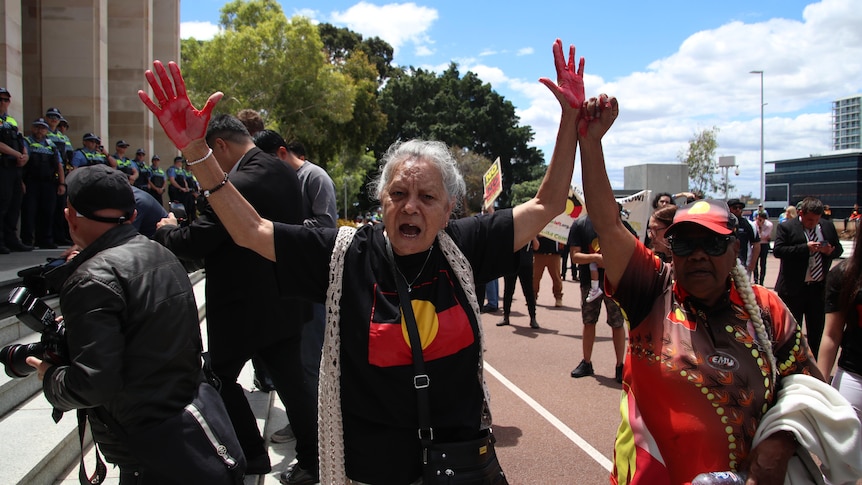 An Aboriginal woman with red ink on her hands at a protest