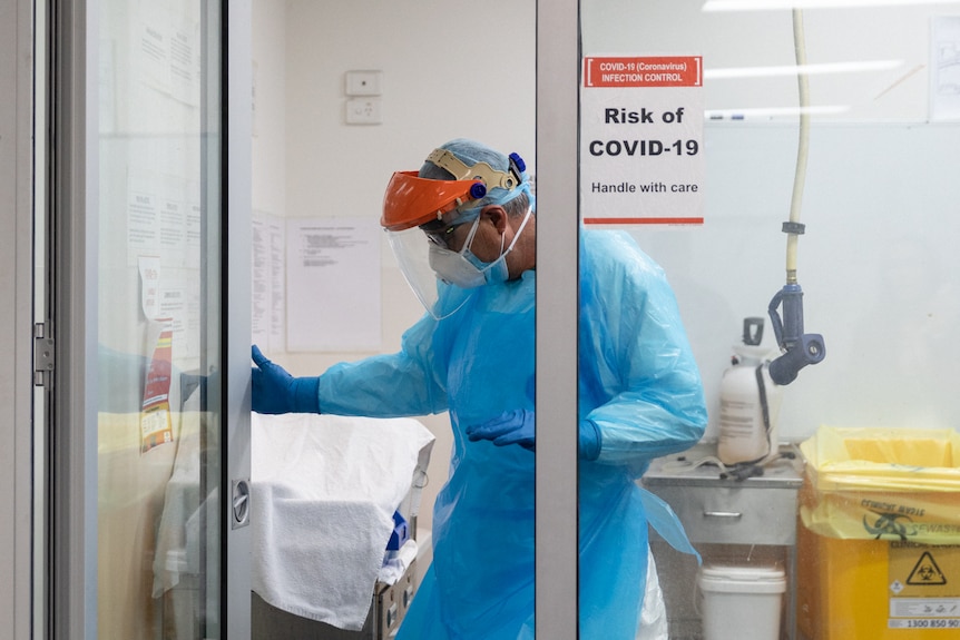 An embalmer at a morgue in protective equipment