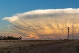 Magnificently huge storm cloud lit up with beautiful sunset colours