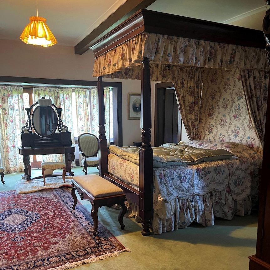 Une chambre vintage avec un lit à baldaquin et des rideaux fleuris.
