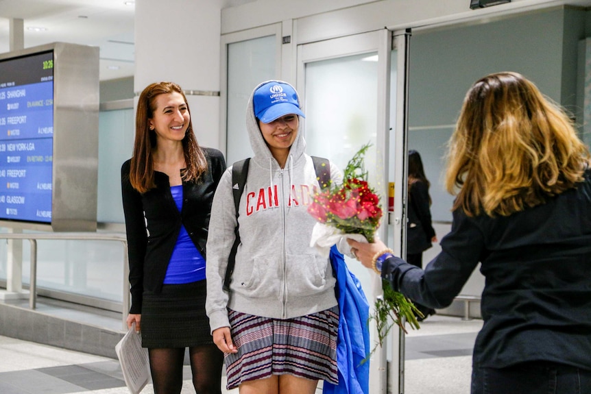 A smiling Rahaf Alqunun received a bunch of flowers at the airport.