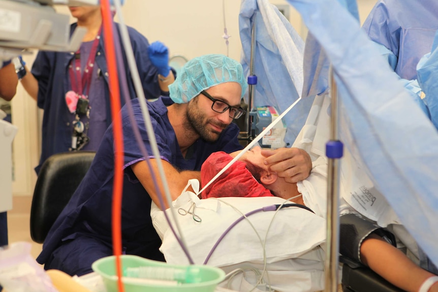 Photo of a couple comforting each other in the delivery room of a hospital.