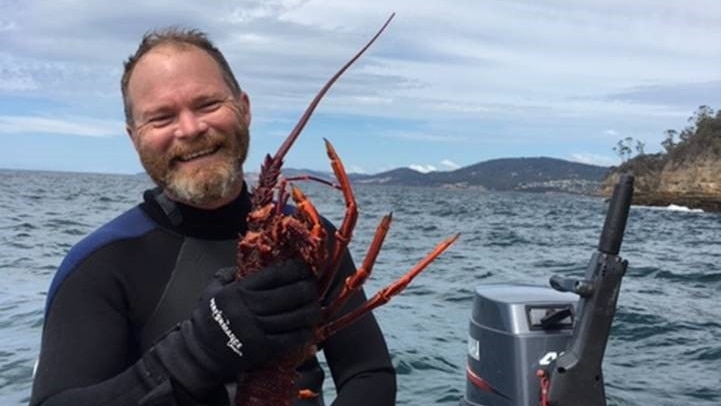 Leon Compton holds a crayfish on a boat