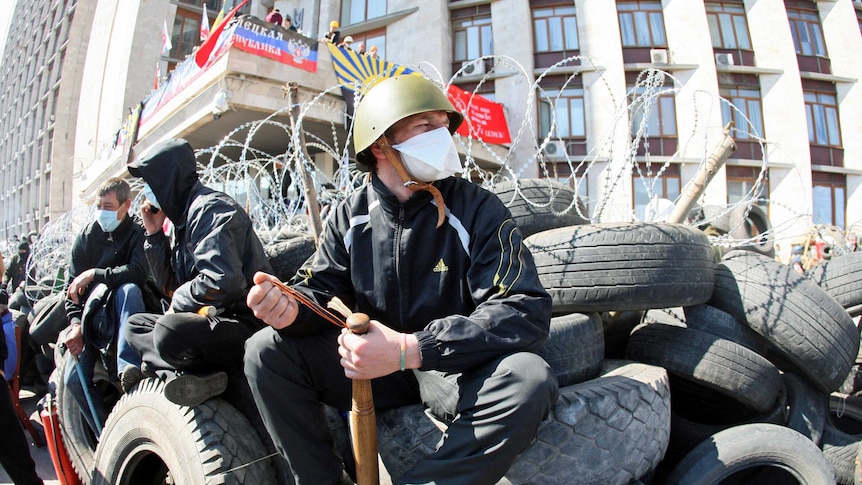 A pro-Russian militant holding a bat guards a barricade in front of the Donetsk regional administration building.