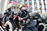 A pro-Russian militant holding a bat guards a barricade in front of the Donetsk regional administration building.