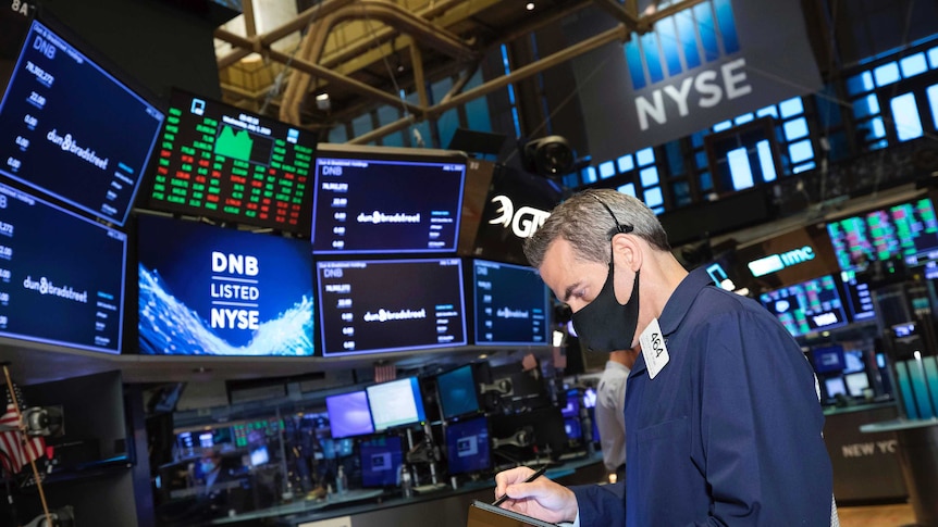 Trader Gregory Rowe works on the floor of the New York Stock Exchange by looking down at a tablet