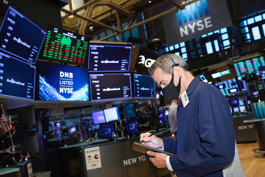 Trader Gregory Rowe works on the floor of the New York Stock Exchange by looking down at a tablet