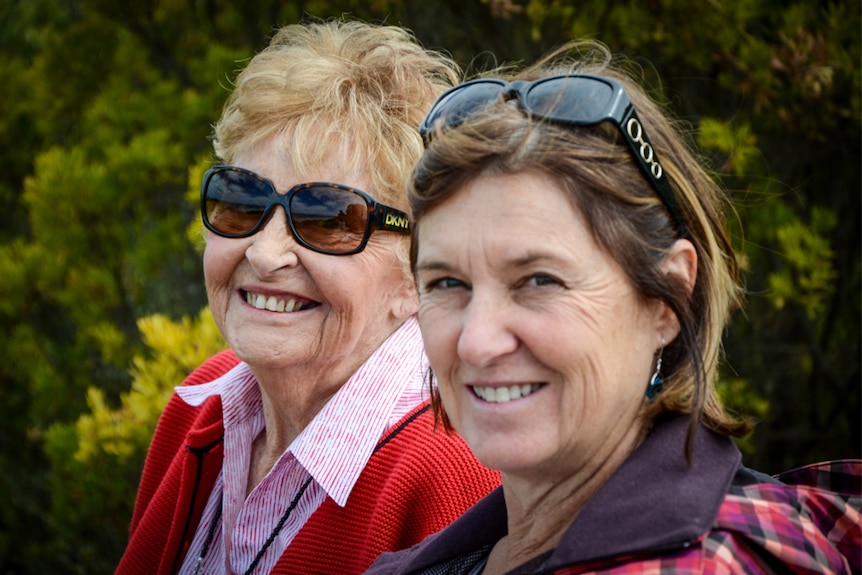 A photo of two women in an outdoor setting, both wearing sunglasses.