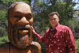 Aboriginal man Max Dillion with large wooden statue of Aboriginal Dreaming God Jabreen which has an open mouth.