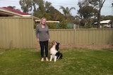 A woman in he backyard with her pet dog. 