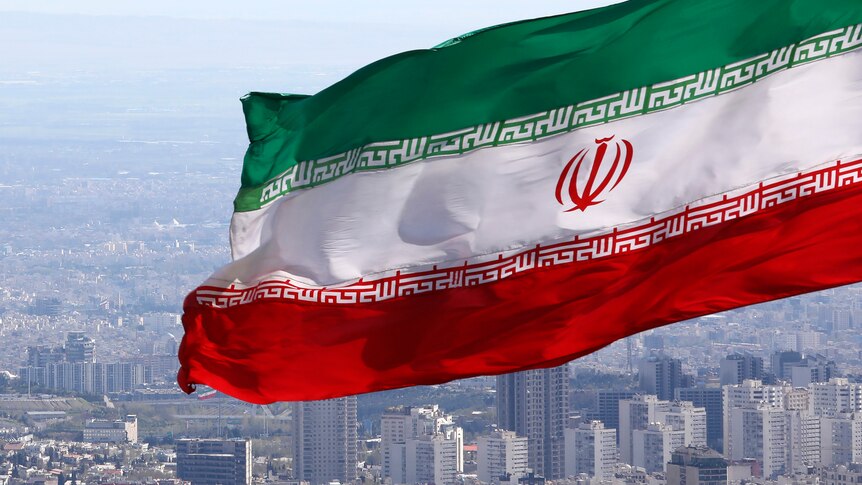 Iran's national flag waves as the streets of Tehran are seen in the distance.