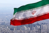 Iran's national flag waves as the streets of Tehran are seen in the distance.