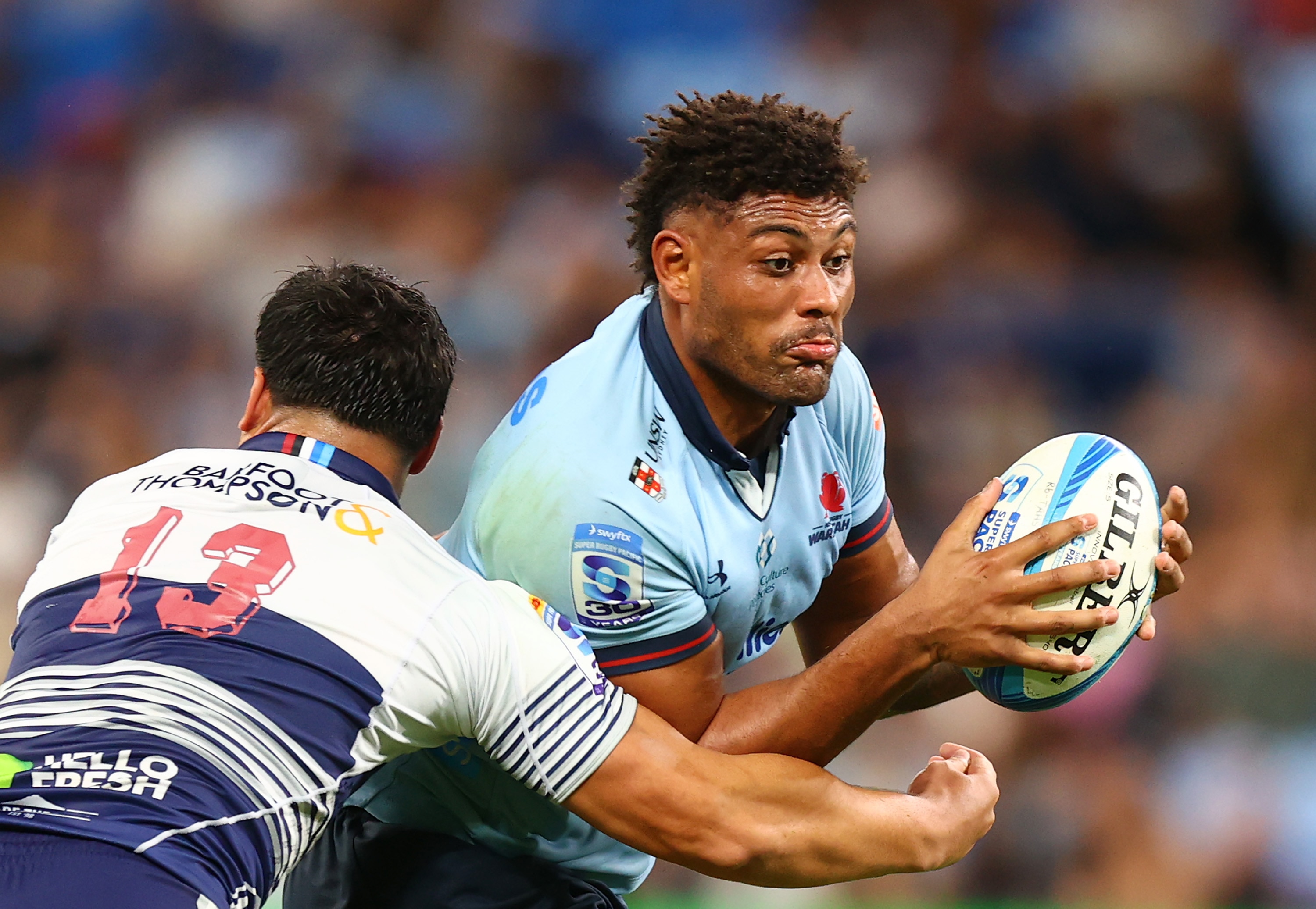 A footballer looks to burst through a tackle.