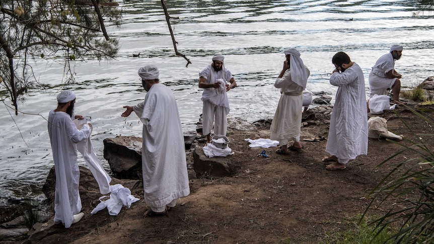 Mandaean men dressed in white traditional clothing prepare to be baptised on the Nepean river in Penrith.