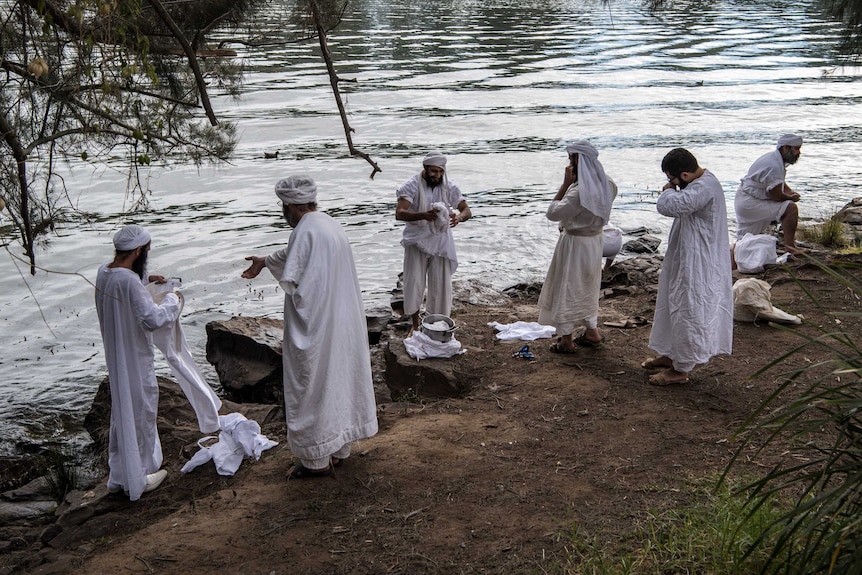 Mandaean men dressed in white traditional clothing prepare to be baptised on the Nepean river in Penrith.