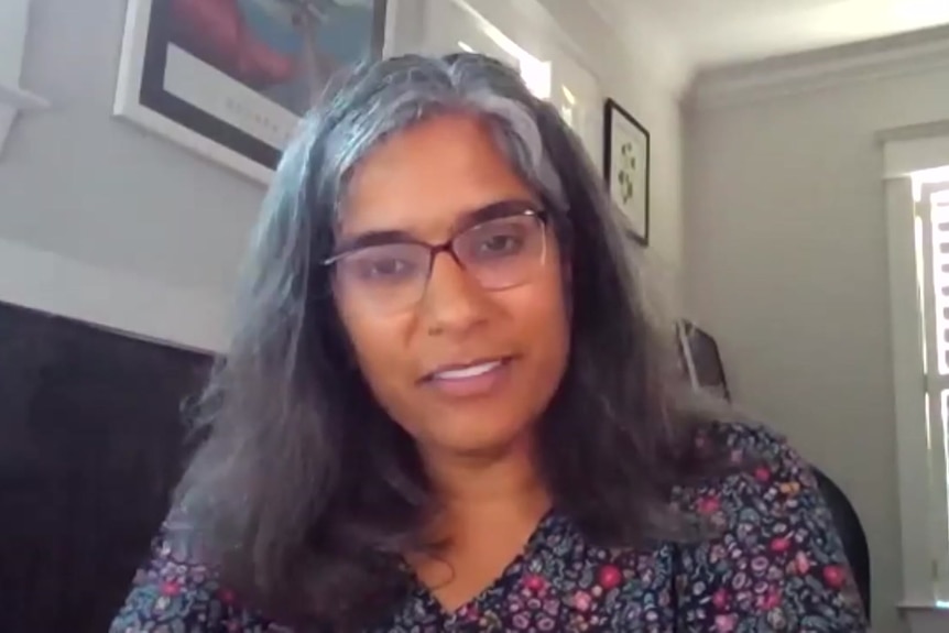 A woman wearing glasses and a floral top.