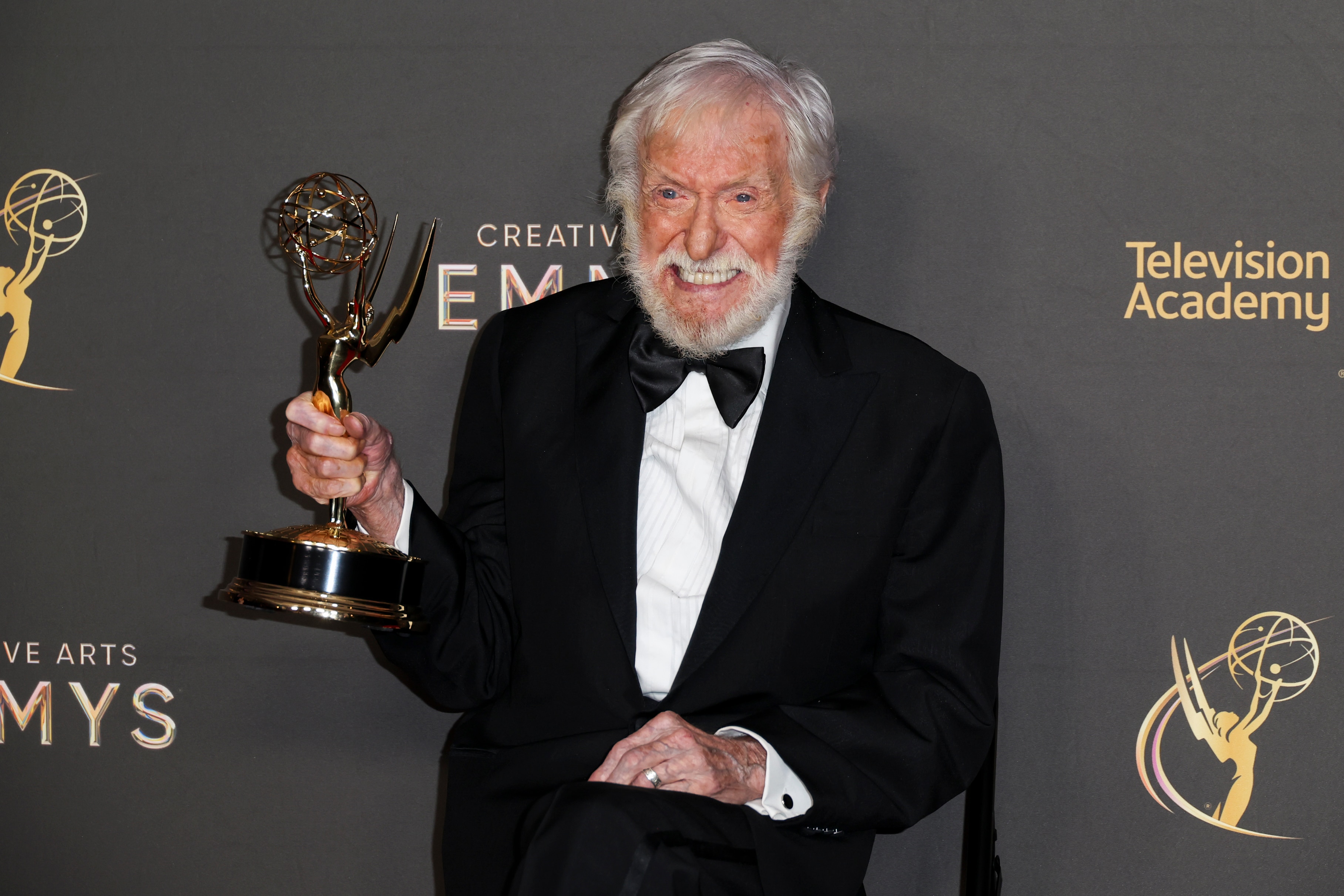 Actor Dick Van Dyke holding an Emmy Award while wearing a tuxedo