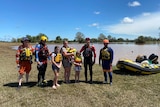 people standing together earing life jackets with an inflatable rescue boat with floodwater in the background