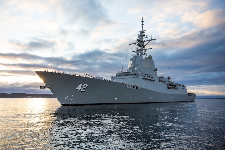 A large war ship is seen under a cloudy sky. 