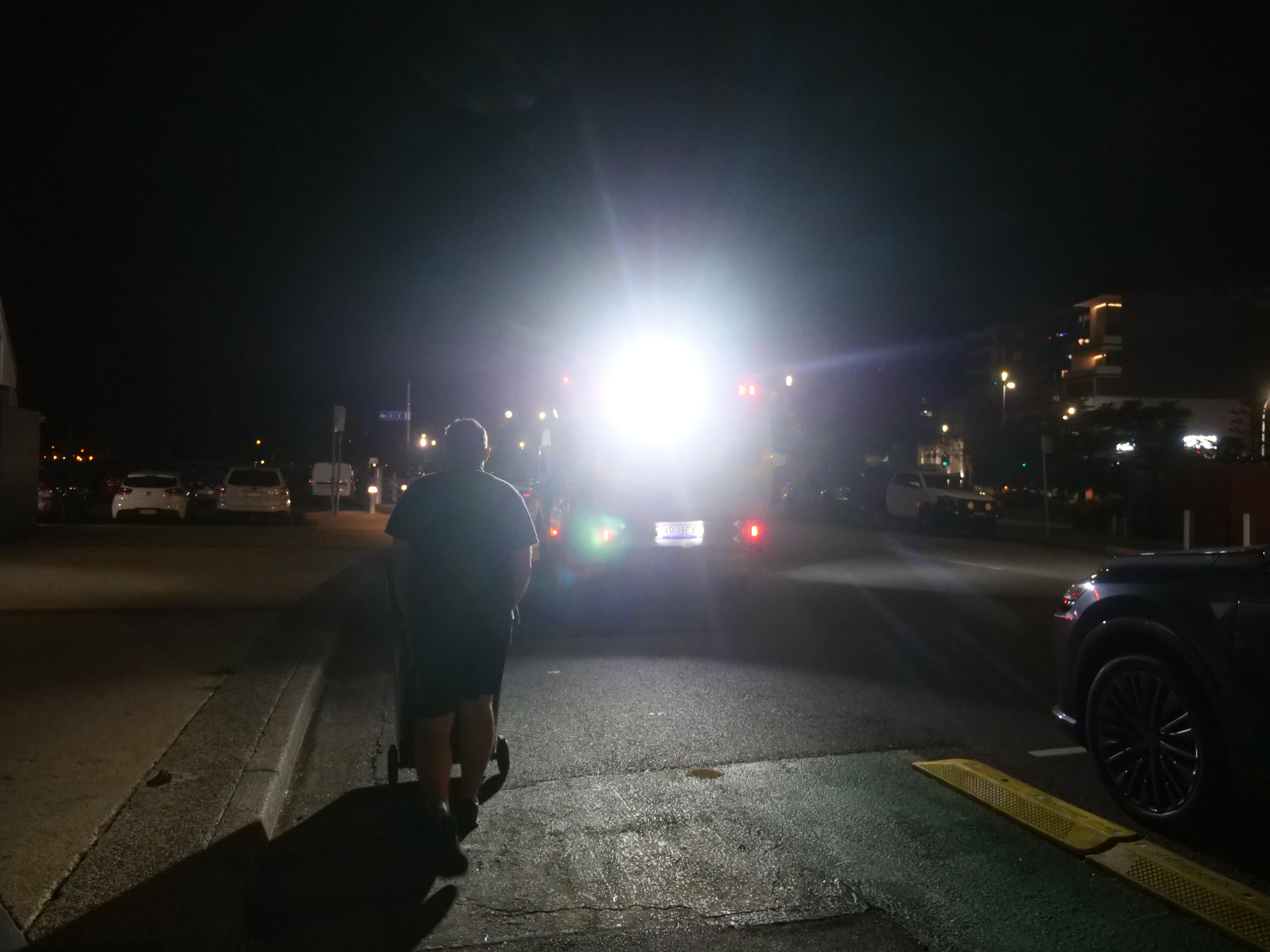 Un hombre empuja un contenedor hacia un camión con una luz brillante