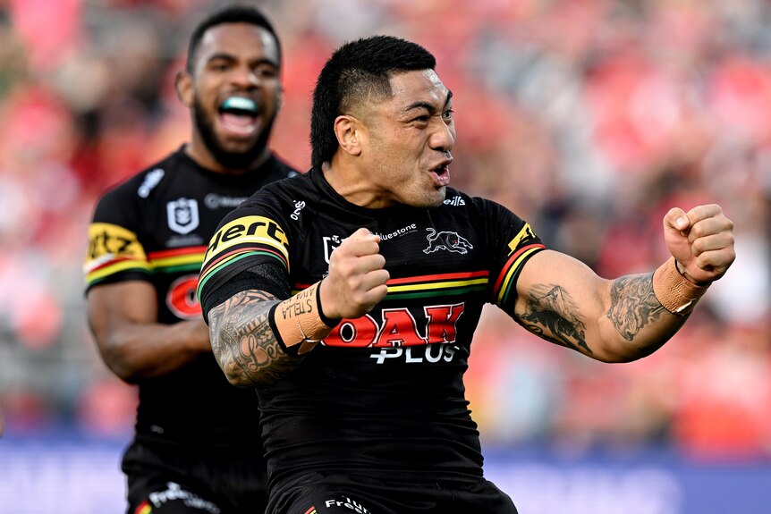 A Penrith NRL player pumps his fists as he celebrates a try against the Dolphins.