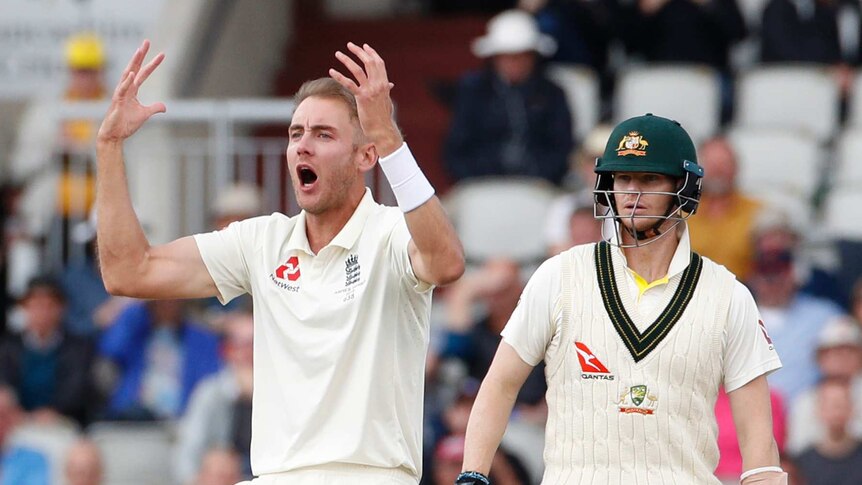 England bowler Stuart Broad shouts and puts both hands in the air as Australia batsman Steve Smith stands behind him.